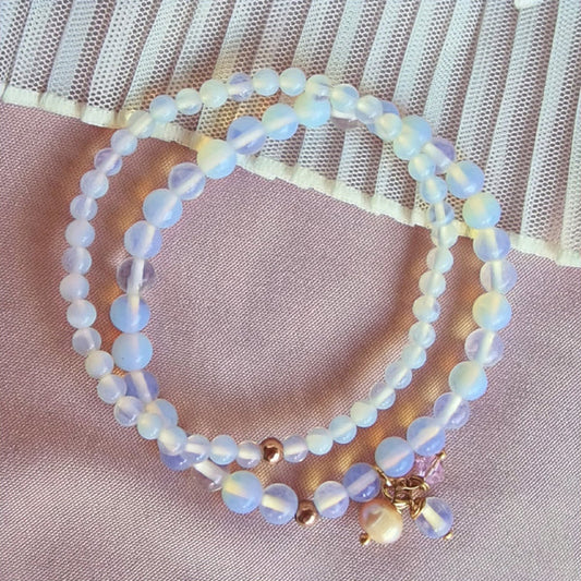 A luminous moonstone pendant glowing against a dark velvet background, surrounded by scattered moonstones and silver accents