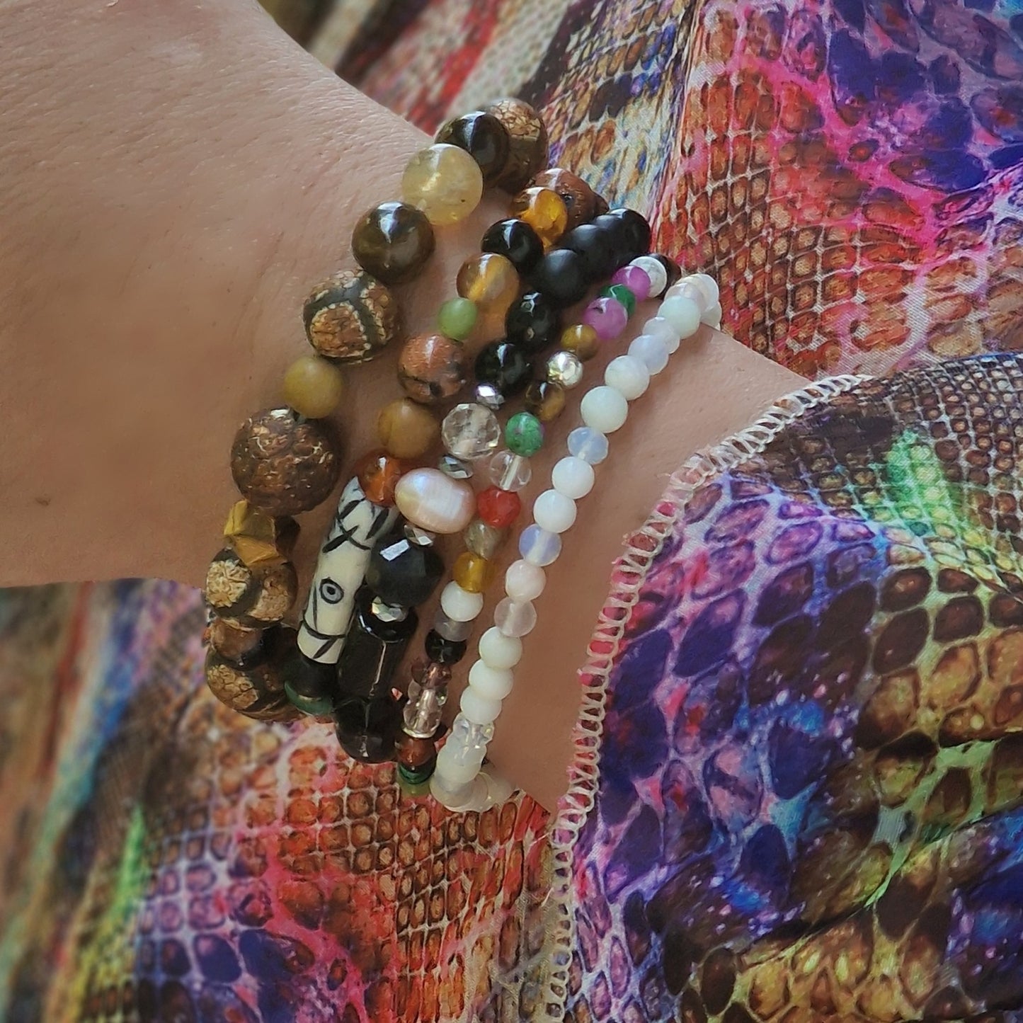 Overhead shot of the full Anri Zenya 5-bracelet stack on a feminine wrist, each gemstone bracelet layered for a balanced, elegant look